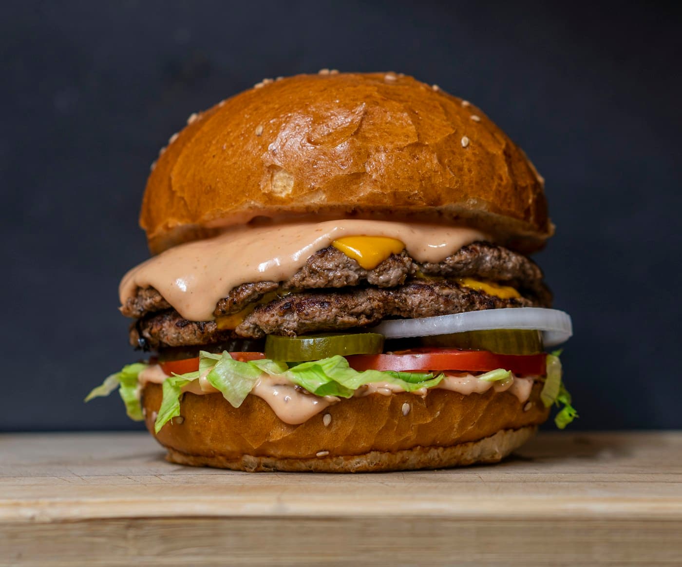 A freshly prepared burger with cheese, lettuce and tomato